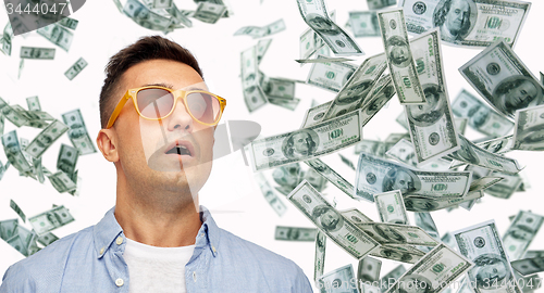 Image of surprised man under dollar money rain