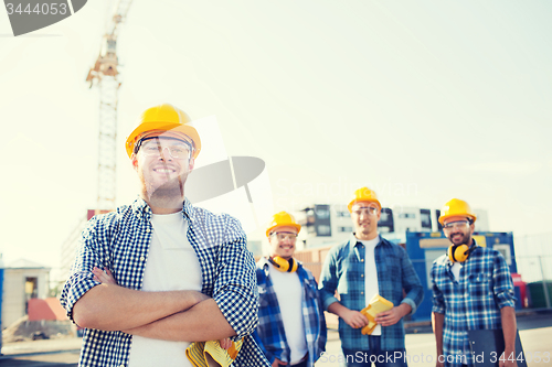 Image of group of smiling builders in hardhats outdoors