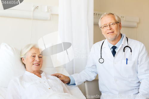 Image of doctor visiting senior woman at hospital ward