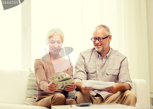 Image of senior couple with money and calculator at home