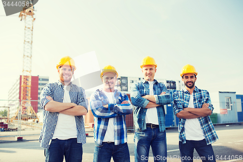 Image of group of smiling builders in hardhats outdoors