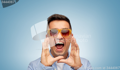 Image of face of angry shouting man in shirt and sunglasses