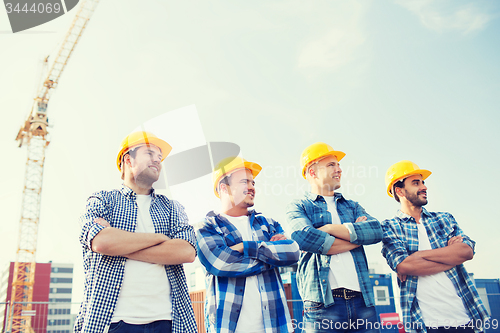 Image of group of smiling builders in hardhats outdoors