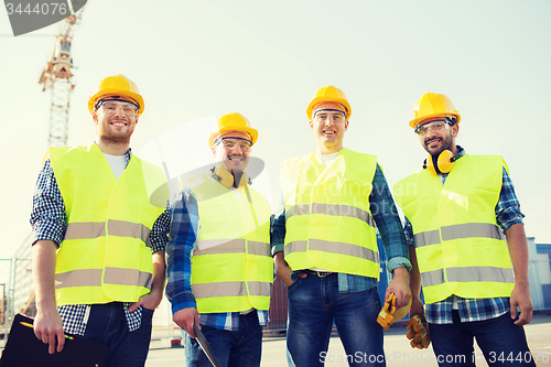 Image of group of smiling builders with tablet pc outdoors