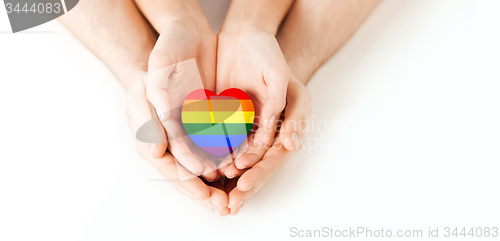 Image of male and female hands holding rainbow heart