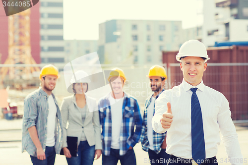 Image of group of smiling builders in hardhats outdoors