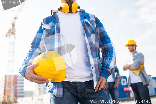 Image of close up of builder holding hardhat at building