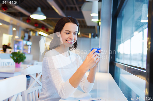 Image of smiling woman with smartphone at cafe