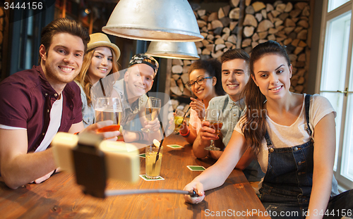 Image of friends with smartphone on selfie stick at bar