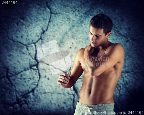 Image of young male bodybuilder applying pain relief gel