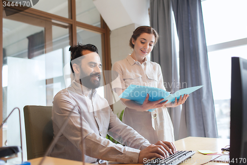 Image of happy creative team with computer in office