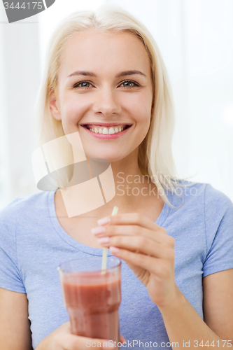 Image of smiling woman drinking juice or shake at home