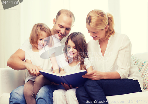 Image of smiling family and two little girls with book