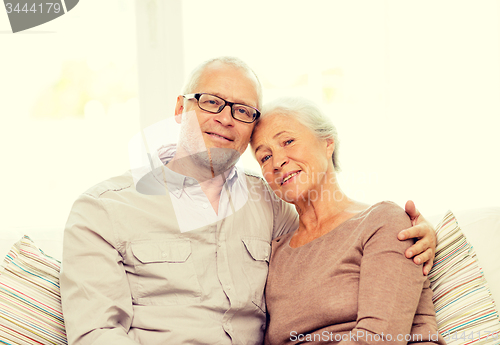 Image of happy senior couple hugging on sofa at home