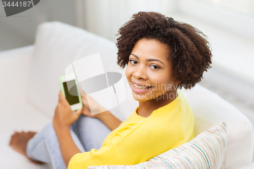 Image of happy african woman with smartphone at home