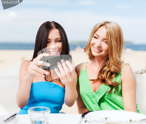 Image of girls taking photo in cafe on the beach