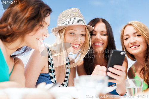 Image of girls looking at smartphone in cafe on the beach