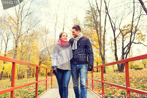 Image of smiling couple hugging on bridge in autumn park