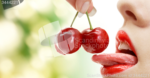 Image of woman mouth with lips and tongue eating cherry