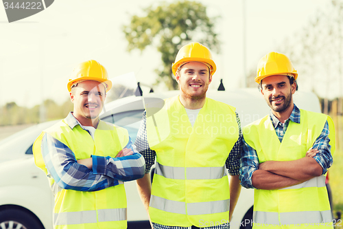 Image of group of smiling builders in hardhats outdoors