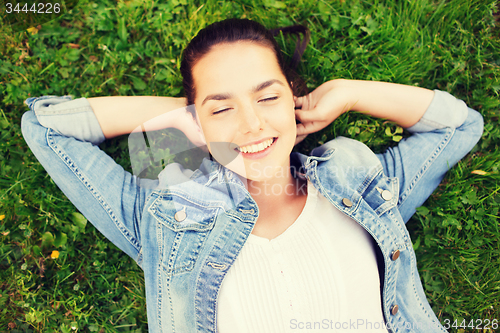 Image of smiling young girl with closed eyes lying on grass