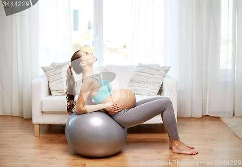 Image of happy pregnant woman exercising on fitball at home