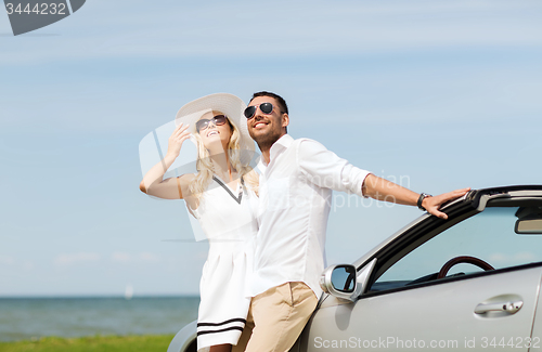 Image of happy man and woman hugging near car at sea