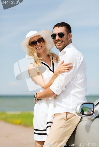 Image of happy man and woman hugging near car at sea