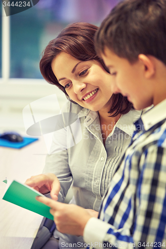 Image of school boy with notebook and teacher in classroom