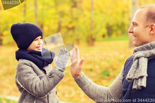 Image of happy father and son making high five in park