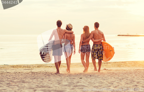 Image of smiling friends in sunglasses with surfs on beach