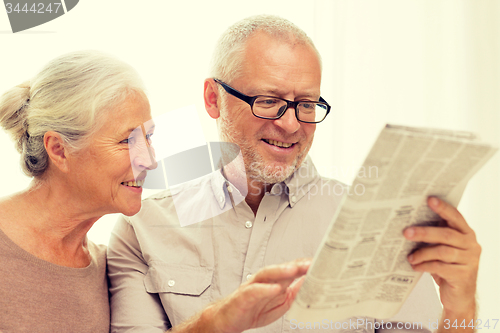 Image of happy senior couple reading newspaper at home