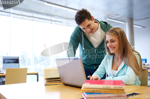 Image of happy students with laptop in library