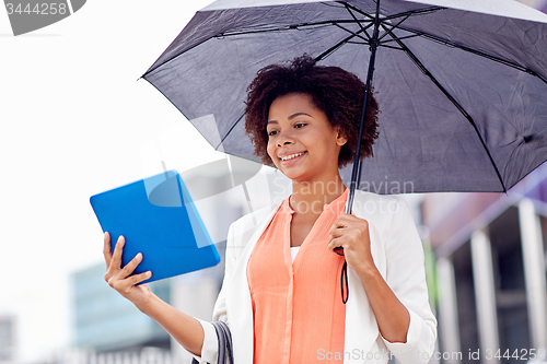 Image of businesswoman with umbrella and tablet pc in city