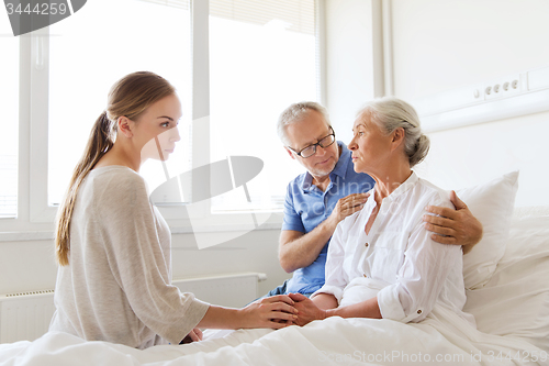 Image of family visiting ill senior woman at hospital