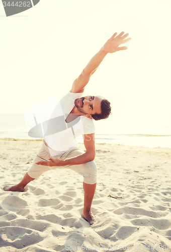 Image of smiling man making yoga exercises outdoors