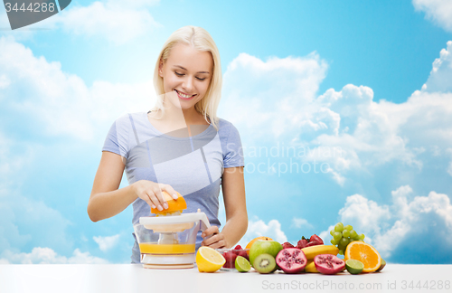 Image of smiling woman squeezing fruit juice over sky