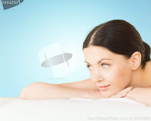 Image of happy beautiful woman lying on massage desk at spa