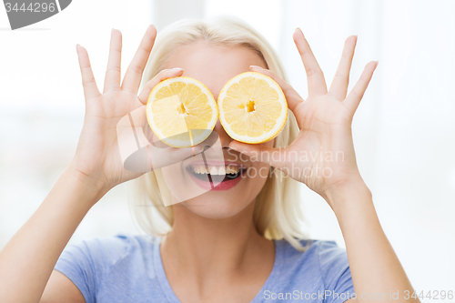 Image of happy woman having fun covering eyes with lemon