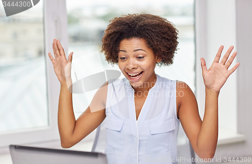 Image of happy african woman with laptop at office