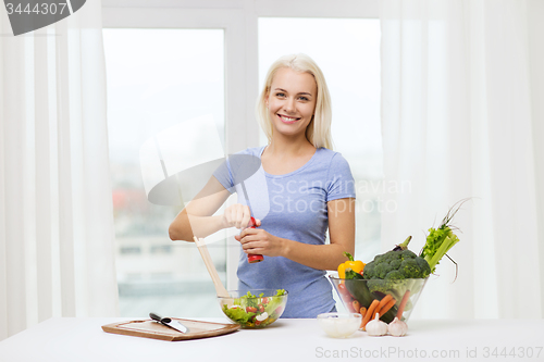 Image of smiling woman cooking vegetable salad at home