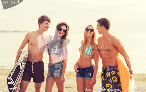 Image of smiling friends in sunglasses with surfs on beach