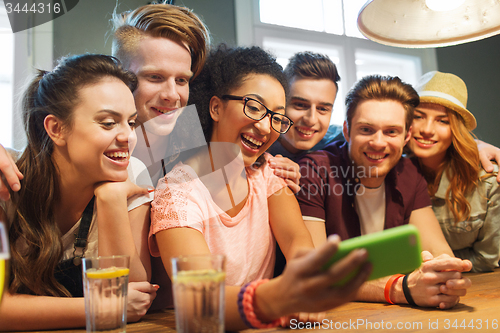 Image of happy friends with smartphone taking selfie at bar