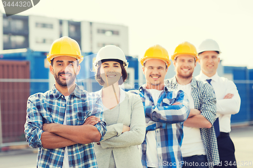 Image of group of smiling builders in hardhats outdoors