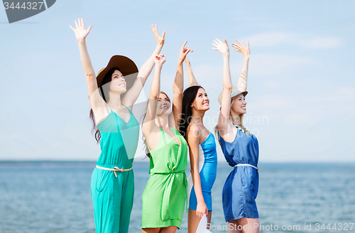 Image of girls looking at the sea with hands up