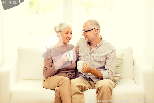 Image of happy senior couple with cups at home