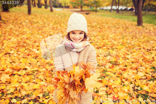 Image of smiling little girl with autumn leaves in park