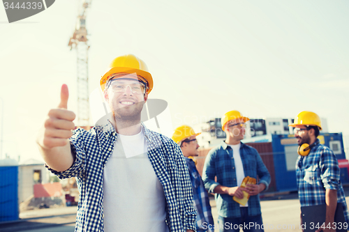 Image of group of smiling builders in hardhats outdoors