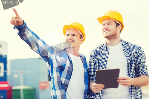 Image of smiling builders in hardhats with tablet pc