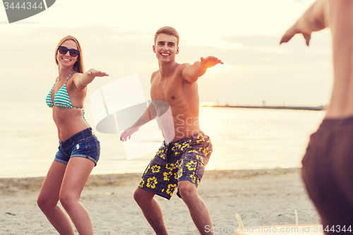 Image of smiling friends in sunglasses with surfs on beach